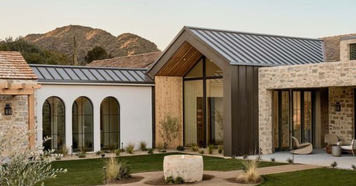 Casa en medio de la naturaleza con aspecto moderno, grandes ventanales, piedra vista y muros blancos exteriores. Gran porche de estar