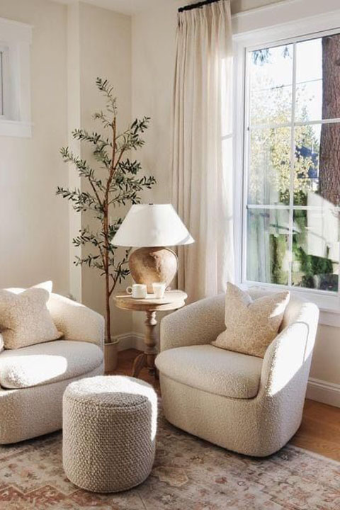 Soul-espacios-0_8B BIBLIOTECA Butaca en ventana soleada con mesita de café con flores y puff